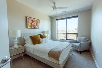 a bedroom with a large window and a ceiling fan